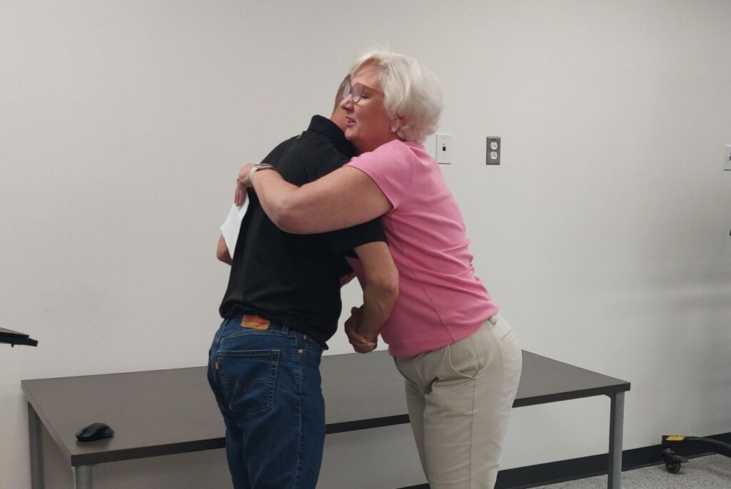 Kris-Tech VP of Sales Kris McCarty hugs Employee of the Month winner Steve Pietrowski.